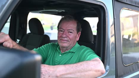 man wearing a green shirt waving in his new car