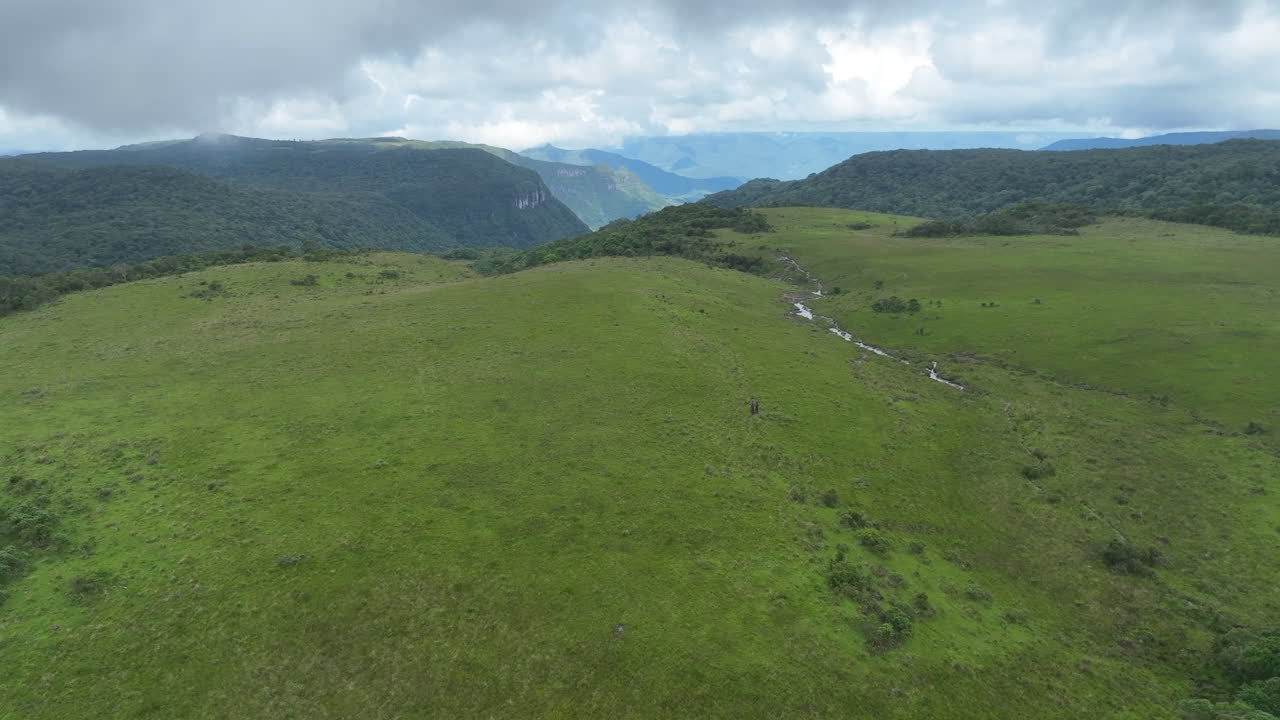 Ripresa aerea cinematografica in 4K con drone e grandangolo che avanza su un rigoglioso altopiano verde rivelando un profondo canyon. Master shot di alta qualità con bitrate elevato per broadcast nel sud del Brasile