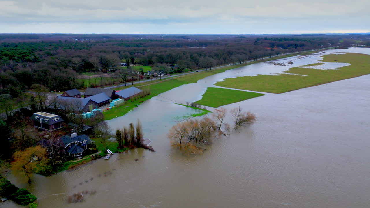 Fixed aerial of water flooding meadow, dike, field, farm, house, floodplain
