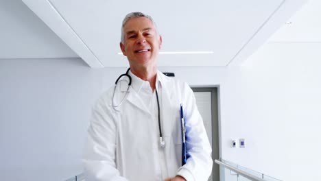 Doctor-looking-at-medical-report-and-smiling-at-camera