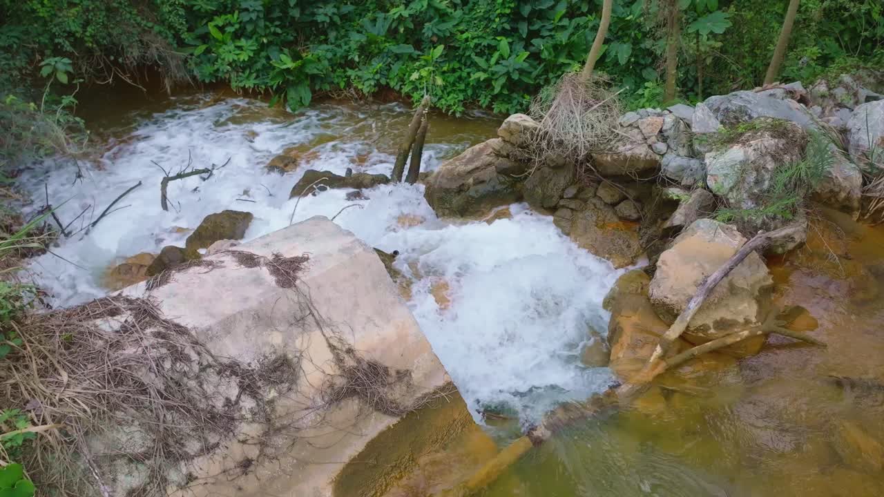 Clear greenish mineral water flowing over rocks in forest near Barrick Gold mining site, Cotuí, Dominican Republic.