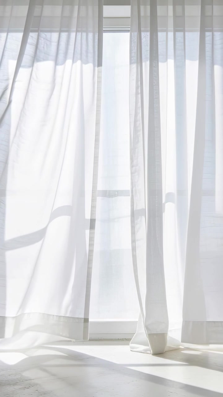 Vertical video: Billowing sheer curtains shifting at window, breeze casting light patterns on floor