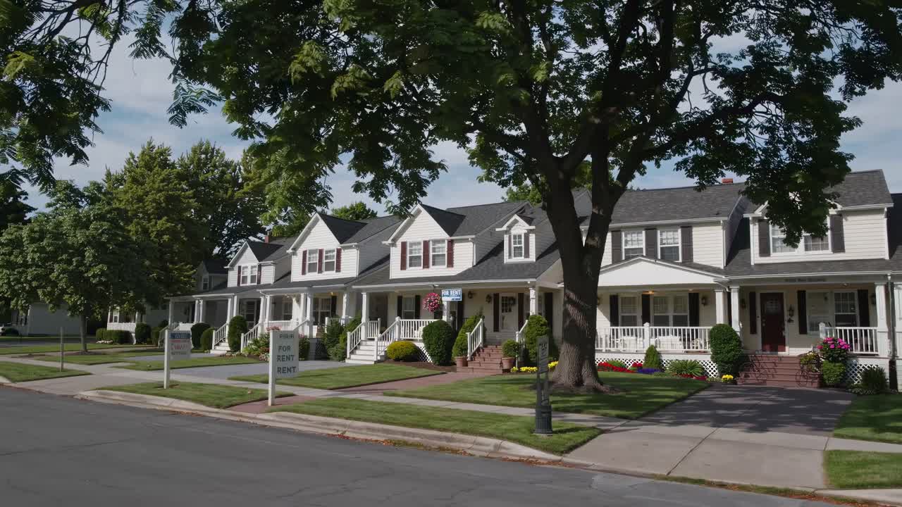 Wide-angle video shot of a suburban street with charming houses, lush trees, and manicured lawns