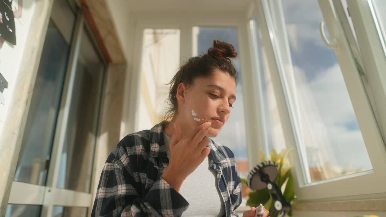 Giovane donna che applica la crema viso come parte della sua routine di cura della pelle.