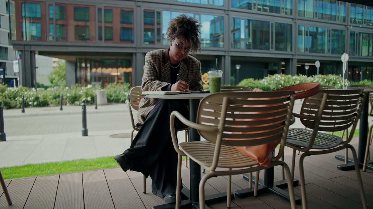 Donna che scrive su un quaderno in un bar all'aperto
