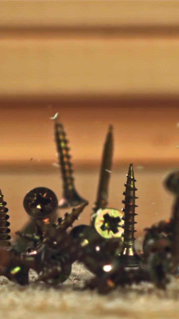 Golden Screws Falling in Slow Motion onto a Wooden Surface