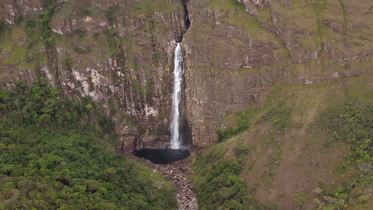 Tall waterfall flowing into dark pool in Serra da Canastra, Brazil, aerial view