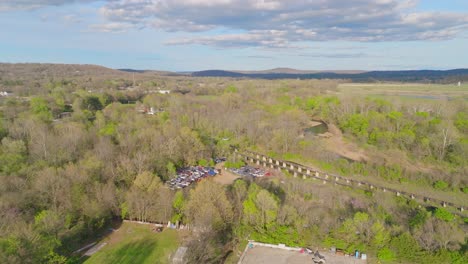 Stunning-Arkansas-landscape,-junkyard-in-foreground,-aerial-wide-shot