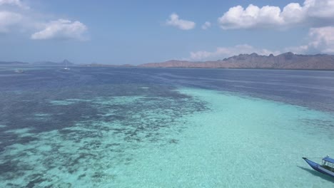 Aerial-drone-shot-of-a-traditional-South-Asian-boat-sailing-through-the-sea-with-clean-and-turquoise-water-on-a-sunny-day