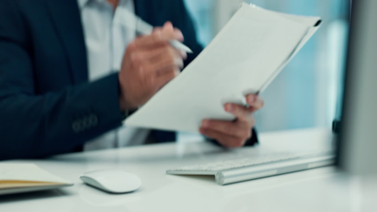 Businessman's Hands Typing on Keyboard and Reviewing Documents