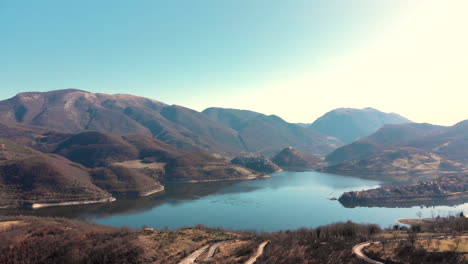 serene lake by the mountains under the clear blue sky during summer in italy. - aerial drone shot
