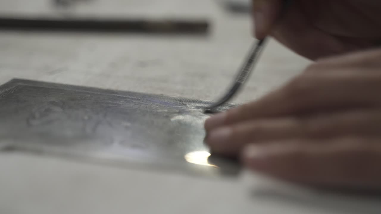 Close up shot of artistic hand made during engraving process using transfer plate, artwork in studio
