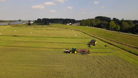 parallel drone shot of two tractors working hay in the netherlands