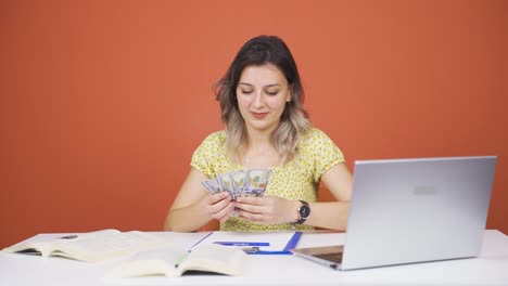 Young-woman-looking-at-laptop-counting-money.