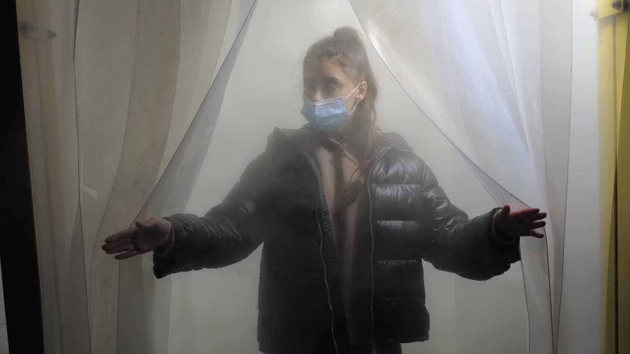 안개 가득 한 커튼 뒤 에 마스크 를 착용 한 소녀