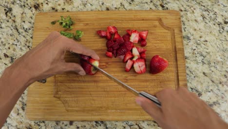 Cutting-red-ripe-strawberries-into-cubes,-POV-shot