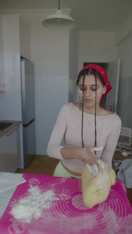 teenage girl kneading dough in kitchen