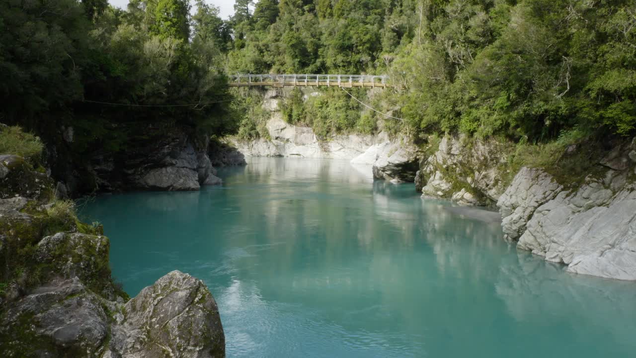 Bridge Over Hokitika Gorge Flowing Through Rocky Banks And Dense Forest In West Coast, New Zealand. - wide shot