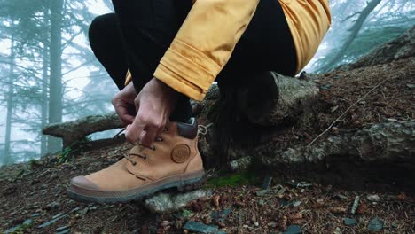 closeup of man sit down wearing hiking shoe tying shoelaces inside forest