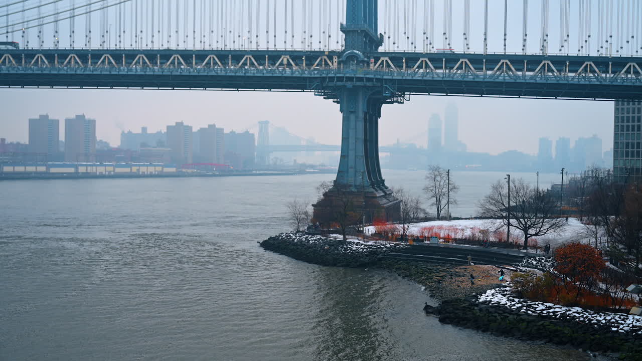 Il lungomare del ponte di Manhattan in inverno. Il lungomare innevato dell'East River con il ponte di Manhattan e gli edifici della città