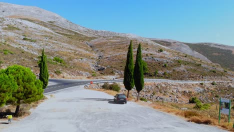 Drone-shot-descending-at-low-height-and-filming-a-car-on-a-roadside-stop-by-the-hills