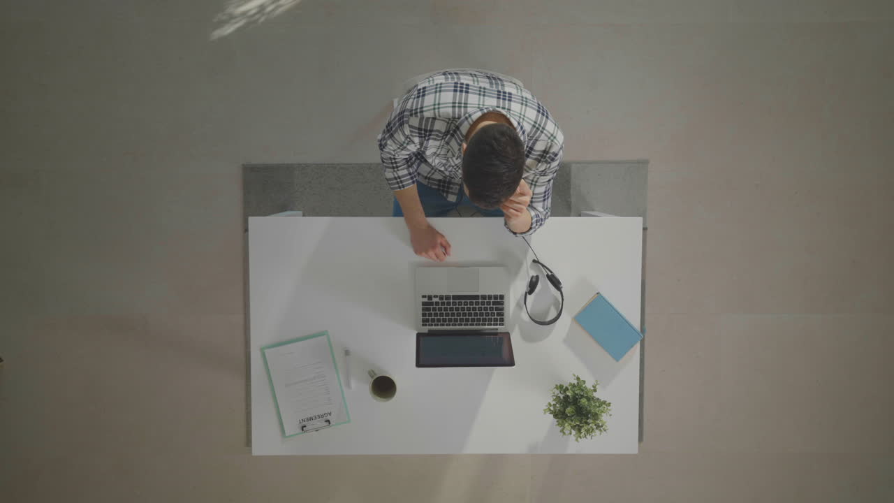 노트북 을 들고 책상 에 앉아 있는 사람