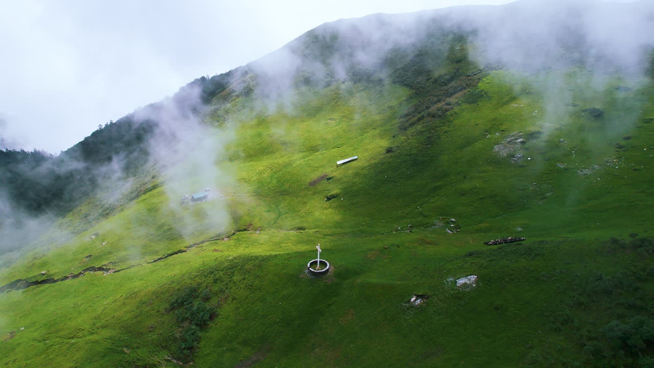 Nepal's clouds cover cross of Jesus Christ in green hill landscapes, blue sky, and sun rays to religious faith in Christianity