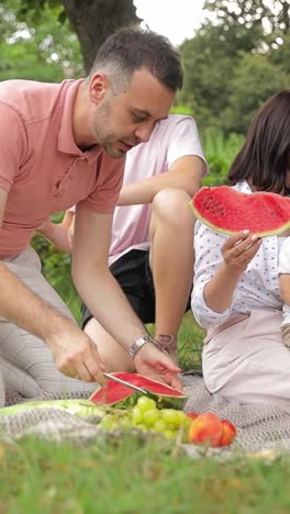 family enjoying a picnic with watermelon outdoors