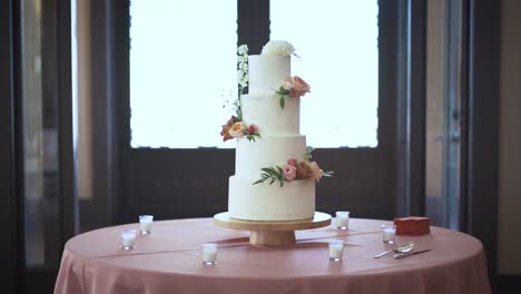 Un-Pastel-De-Bodas-Se-Sienta-En-Una-Mesa-Completa-Con-Decoración-Y-La-Cámara-Se-Acerca-Lentamente-A-La-Dulce-Torre-De-La-Felicidad-Horneada