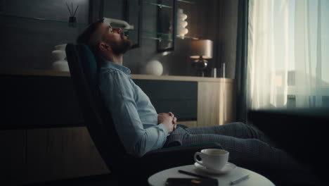 professional financial expert sitting in chair with closed eyes, resting after work and hard trading day. successful businessman in comfortable home office or investment bank office. dolly shot.