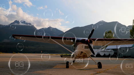 Small-airplane-on-tarmac-with-6G-network-animation-over-mountain-background