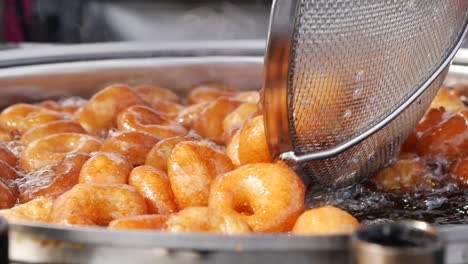 close-up of lokma, turkish fried dough dessert, being cooked in a large pot of oil