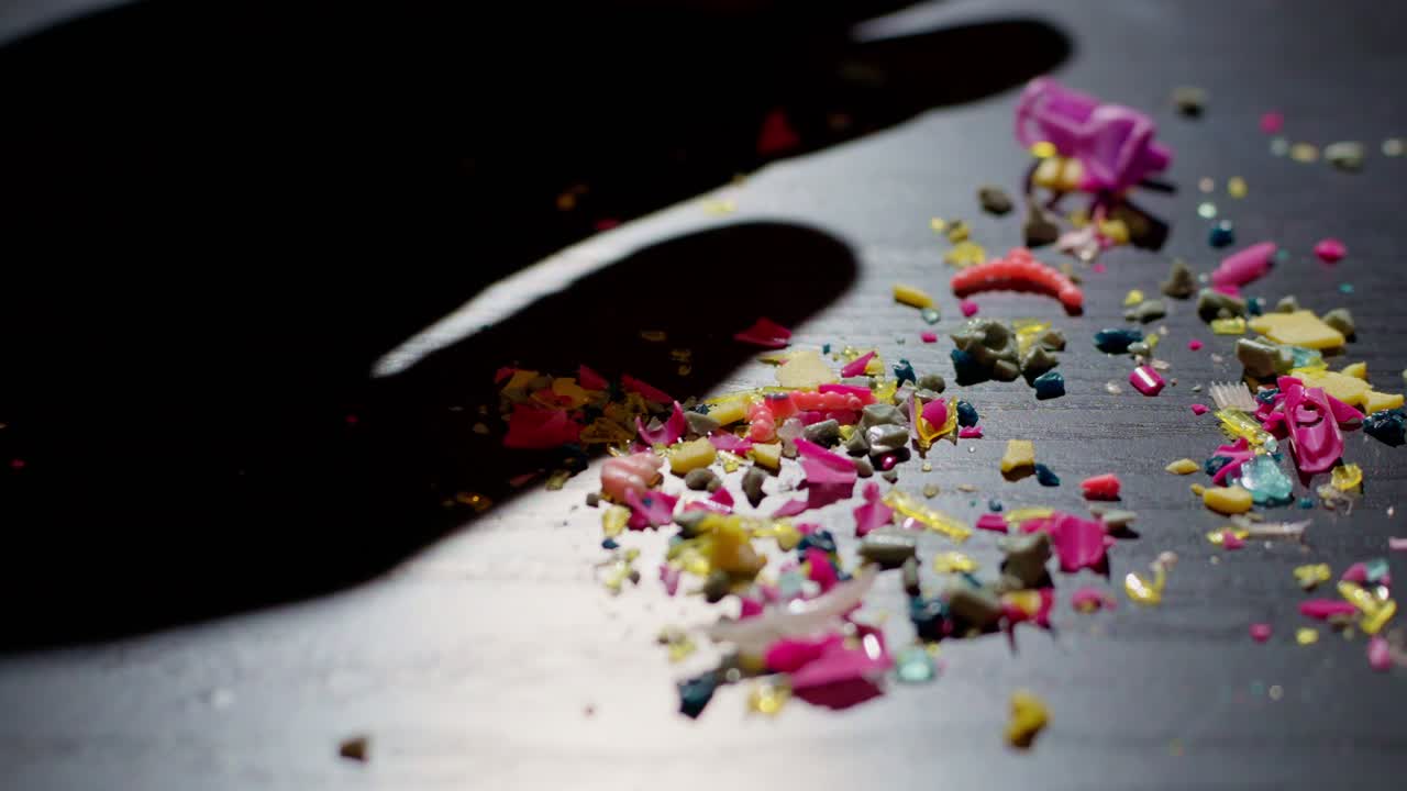 플라스틱 잔해는 극적인 조명 아래 손으로 무더기로 밀려들어 환경 영향과 미세플라스틱 오염을 상징합니다.