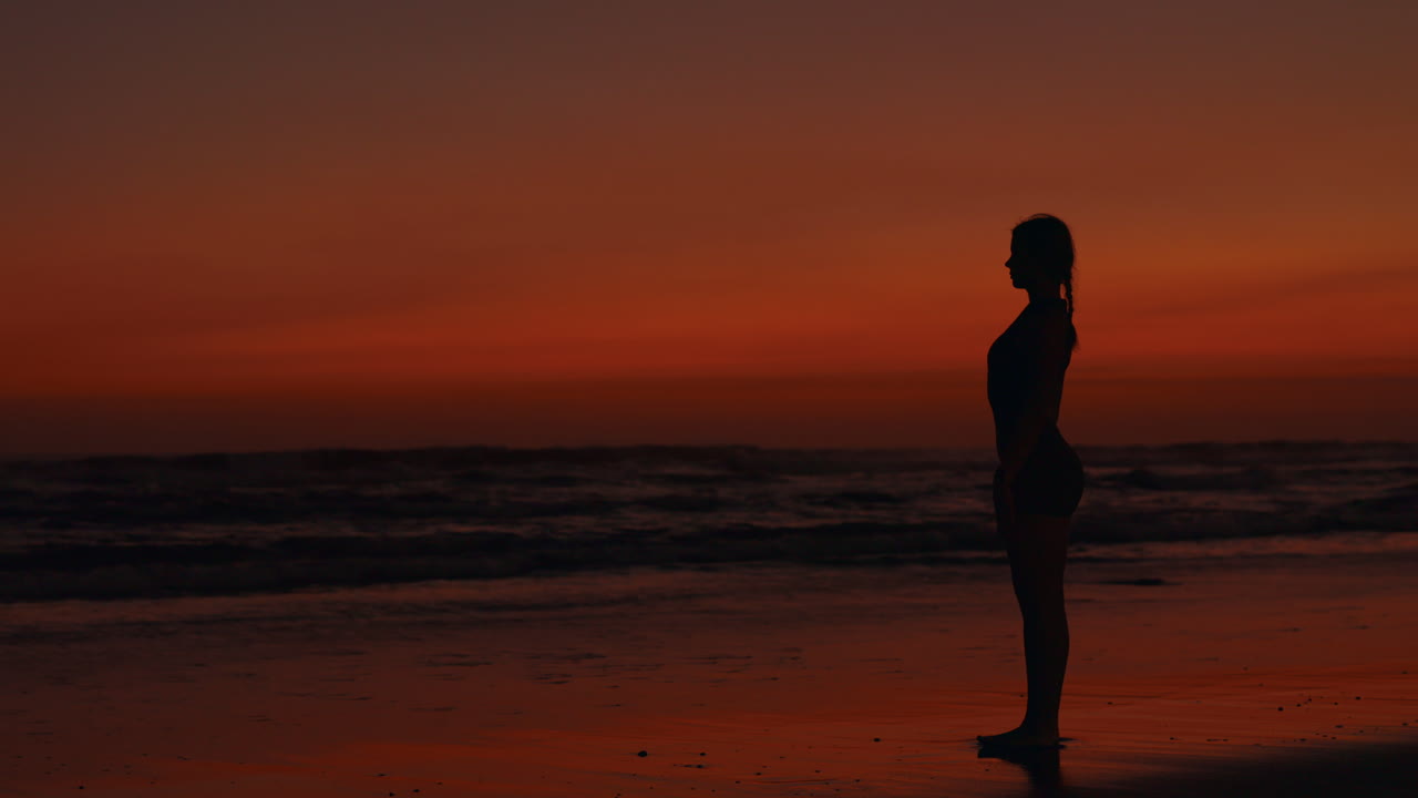 silueta de una mujer haciendo yoga en la playa al atardecer