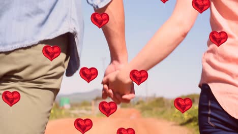 multiple heart balloons floating against mid section of couple holding hands