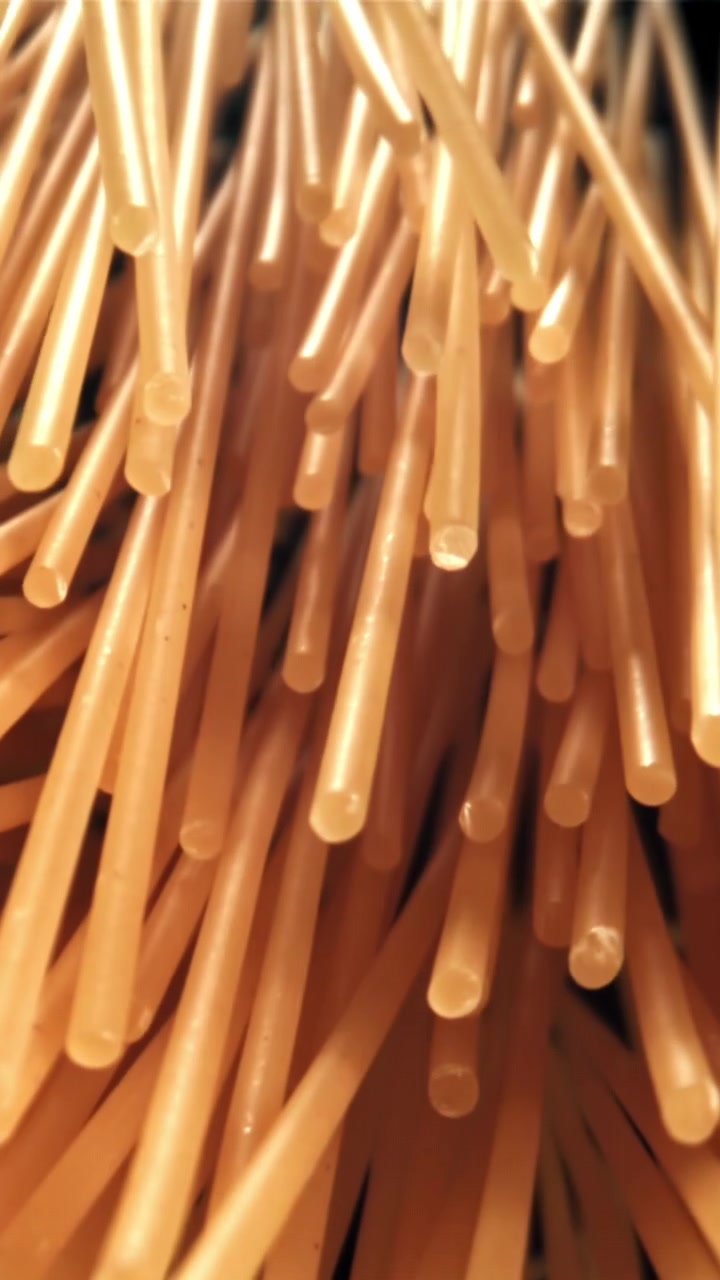 Makrooptagelse af ukogt spaghetti, der stiger op mod sort baggrund