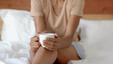 woman enjoying morning coffee in bed, feeling relaxed and content, at home