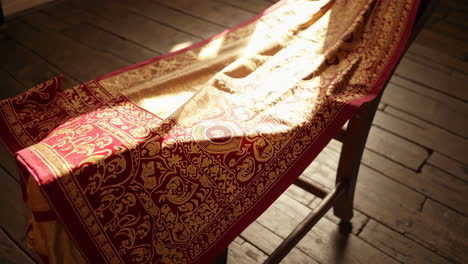 ornate red and gold fabric draped on a chair