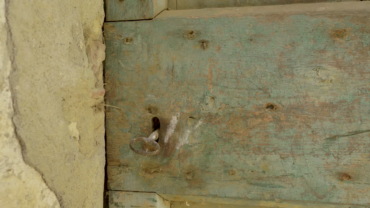 primer plano de una antigua puerta de madera con una llave oxidada en el ojo de la cerradura