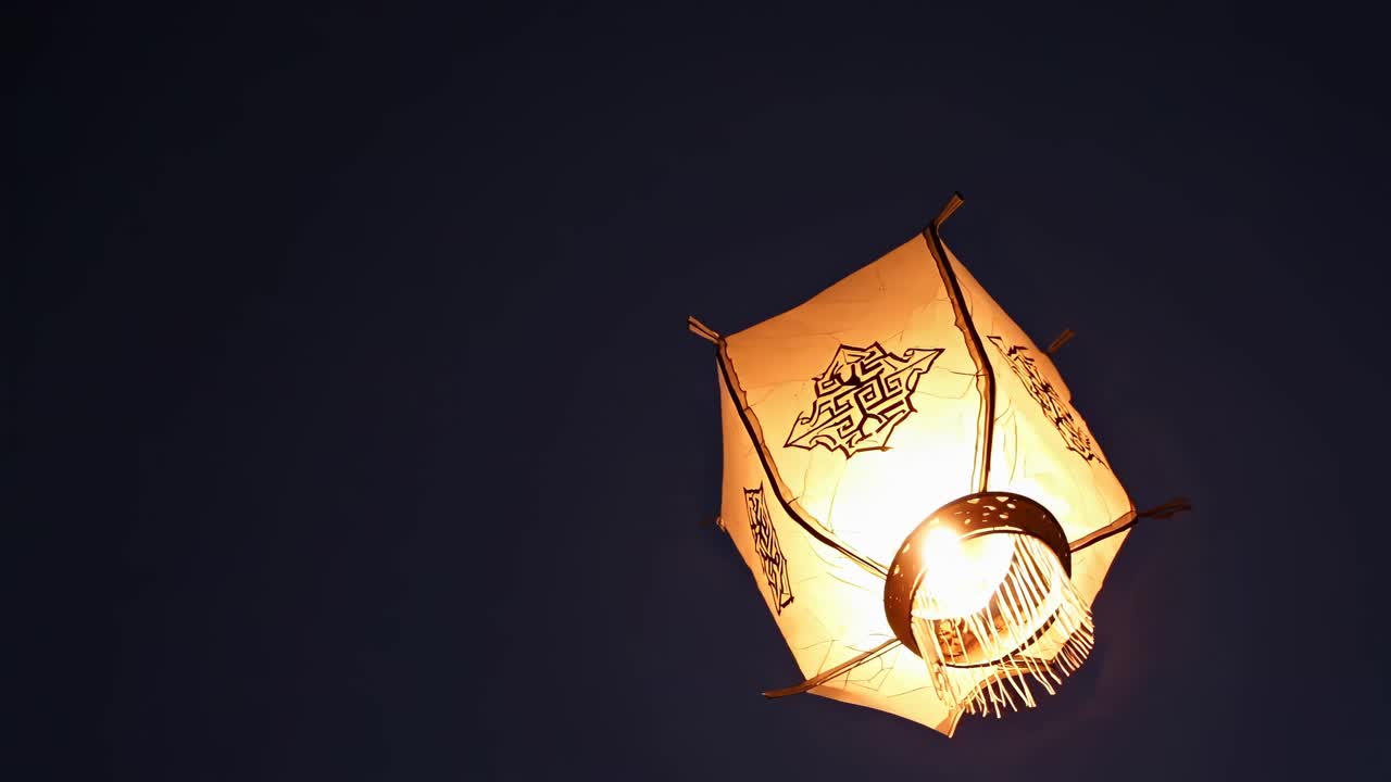 Low-angle shot of a glowing lantern against a dark sky, creating a serene and mystical atmosphere