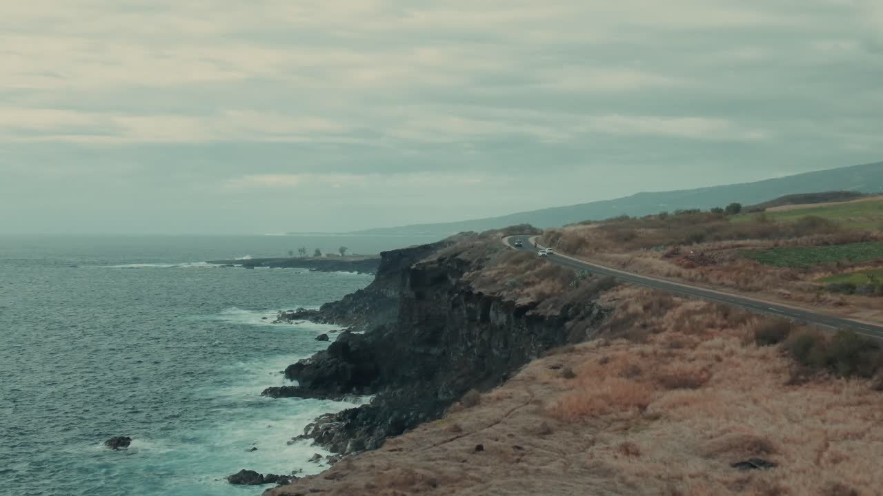 4k Aerial coastal road with volcanic cliffs on cloudy day