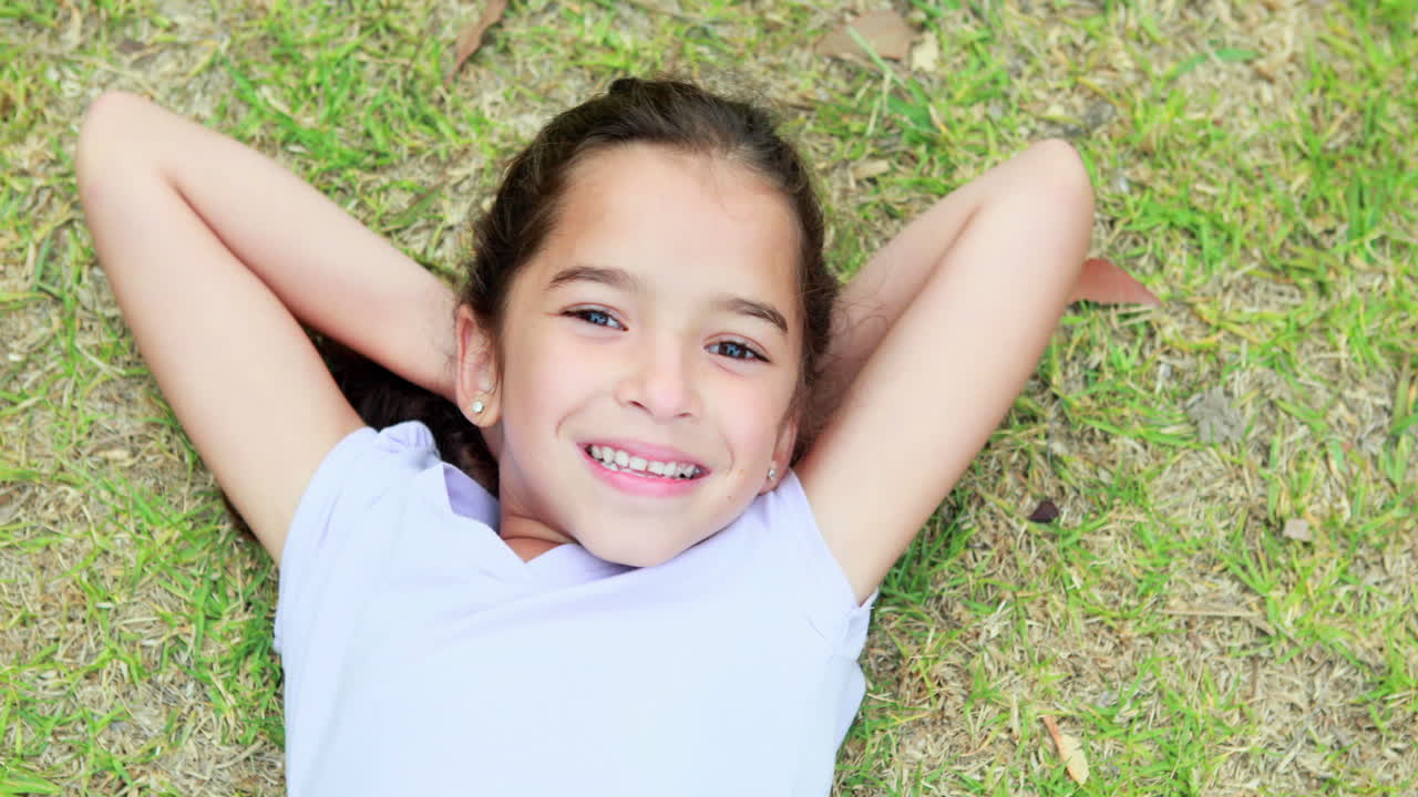 Niña feliz recostada en la hierba y mirando a la cámara