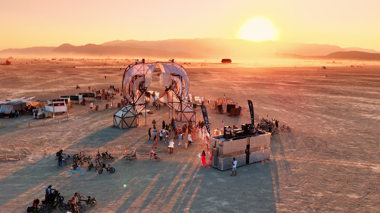 Nevada, USA, 25 August 2025: Aerial drone view of the Burning Man festival at sunrise showing people, bikes, and art structures in the desert
