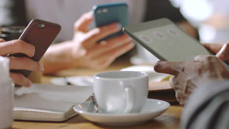personas que colaboran en un café usando teléfonos inteligentes y tabletas