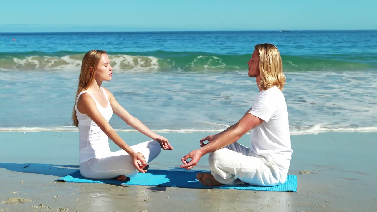 Coppia che pratica yoga in spiaggia