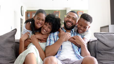 Portrait-of-happy-african-american-daughter-and-son-embracing-parents-on-sofa,-slow-motion