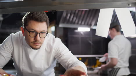 chef serving food on plates in restaurant kitchen