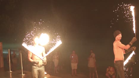 shirtless performer spinning fire at night