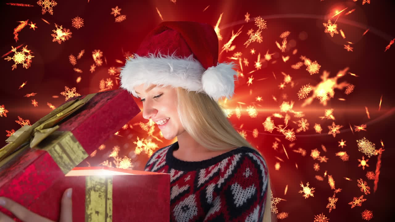 mujer emocionada abriendo una caja de regalos de navidad mágica con copos de nieve de oro