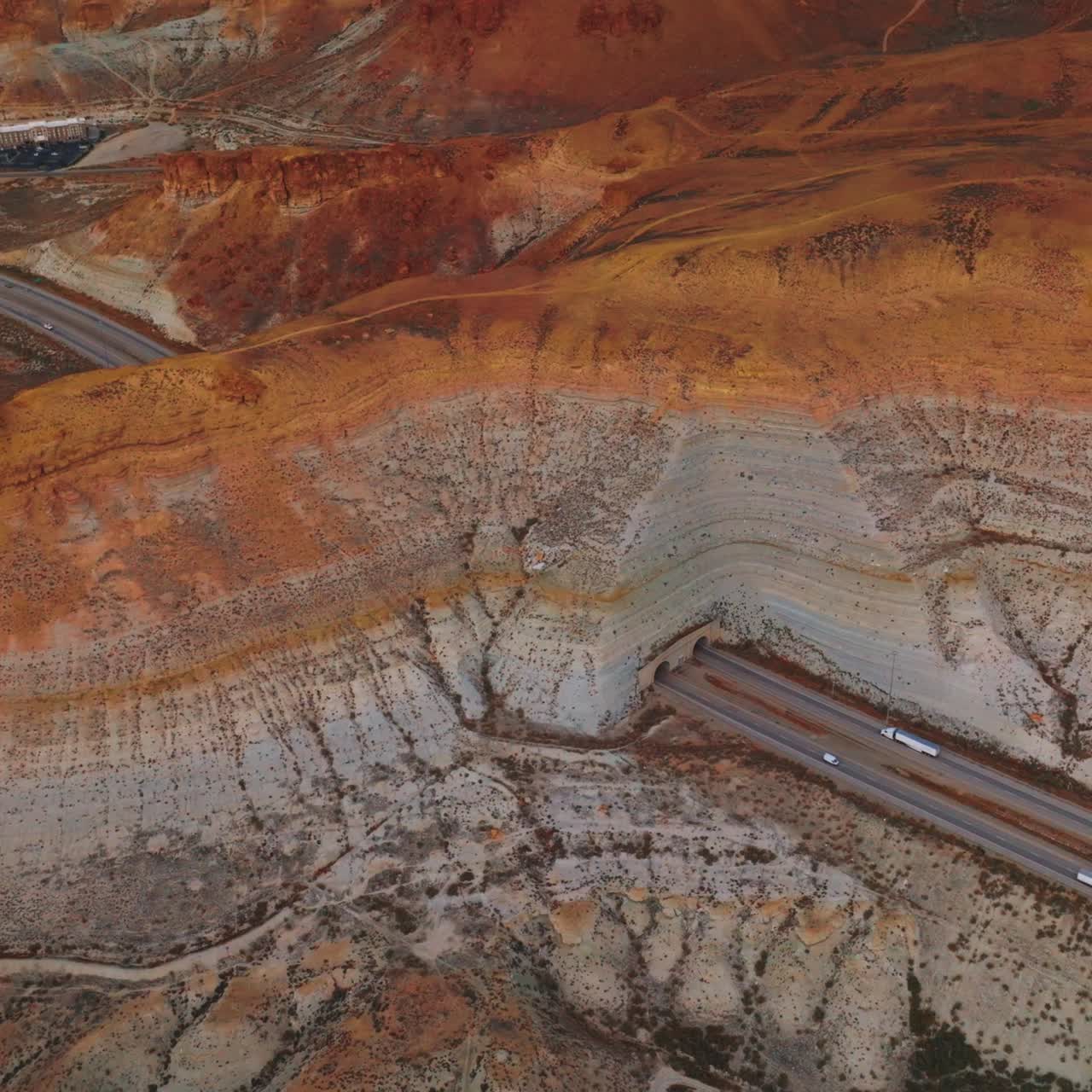 Cars and trucks moving along the tunnels in the mountains of Wyoming, USA. Amazing rocky landscape with town located nearby. Top view